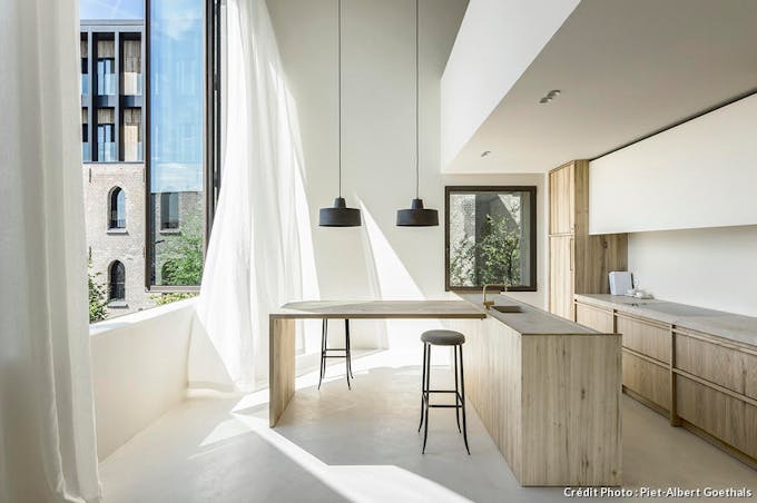 Une cuisine minimaliste en bois clair avec de grandes fenêtres sur l'extérieur 
