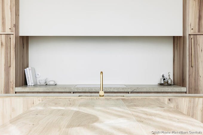Une cuisine minimaliste en bois clair avec une robinetterie dorée