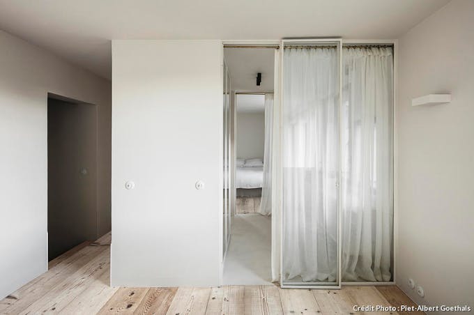 Vues d'une chambre minimaliste et lumineuse dans un cube blanc un sol en bois clair et une baie vitrée minimaliste