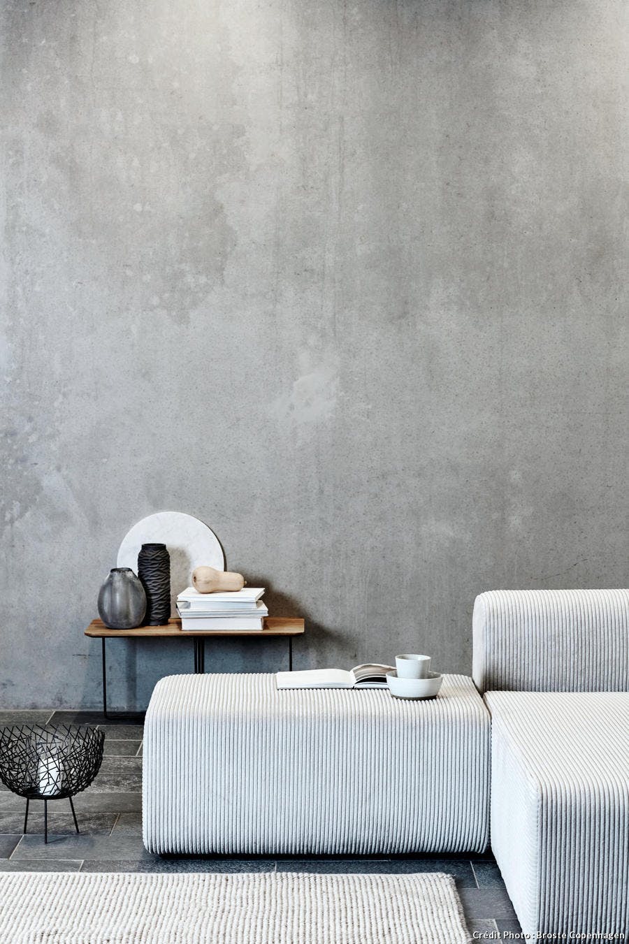 Un salon gris avec mur en béton et canapé en velours côtelé