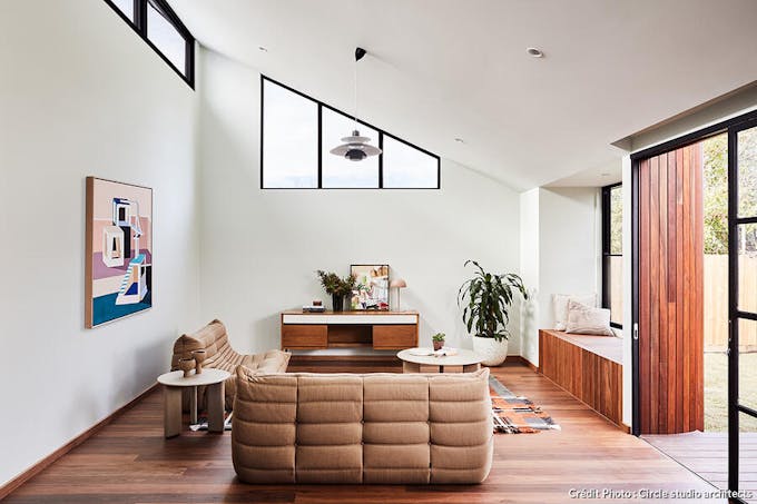 un salon dans une extension avec un parquet en bois chaud et ouvertures vitrées du sol au plafond