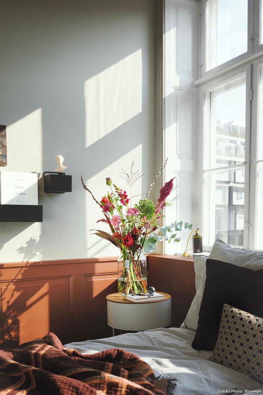 Une chambre teraccotta avec un vase rempli de fleurs et un lit douillet