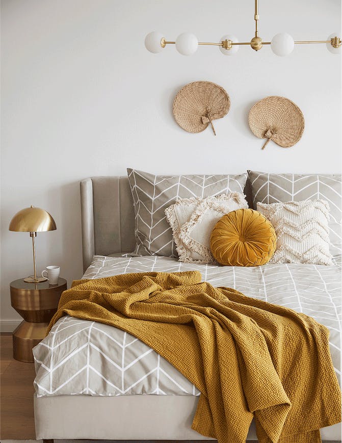 une chambre à coucher de style ethnique avec une lampe de chevet doré sur un tabouret doré
