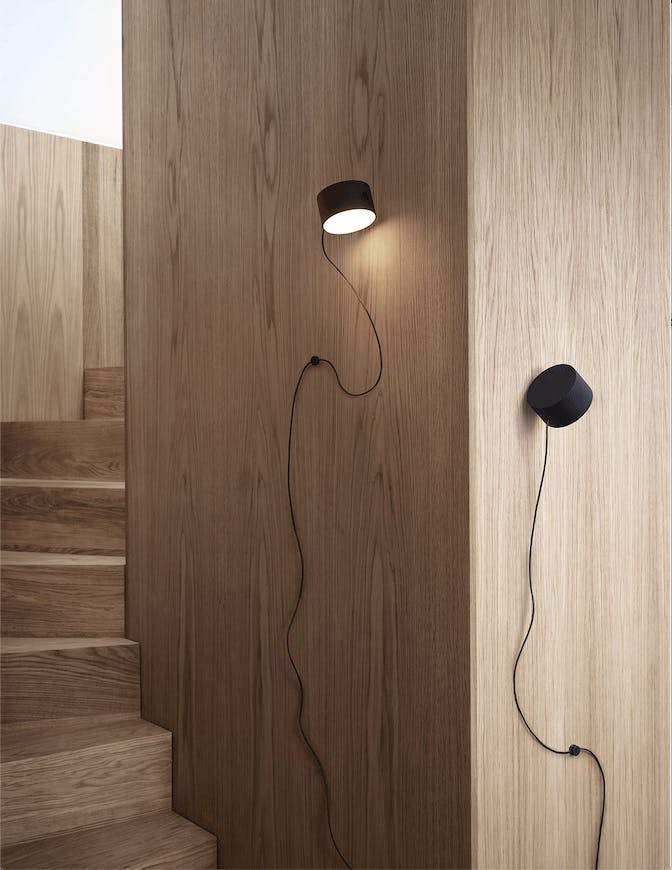 des appliques minimalistes dans un couloir entièrement habillé de bois