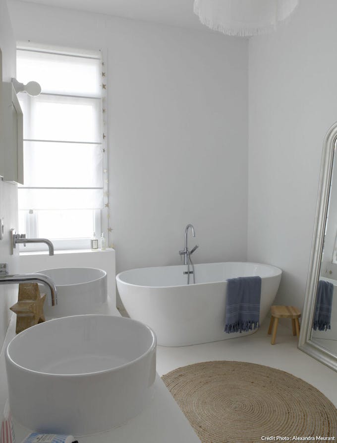 Salle de bains avec baignoire et vasques blanches.
