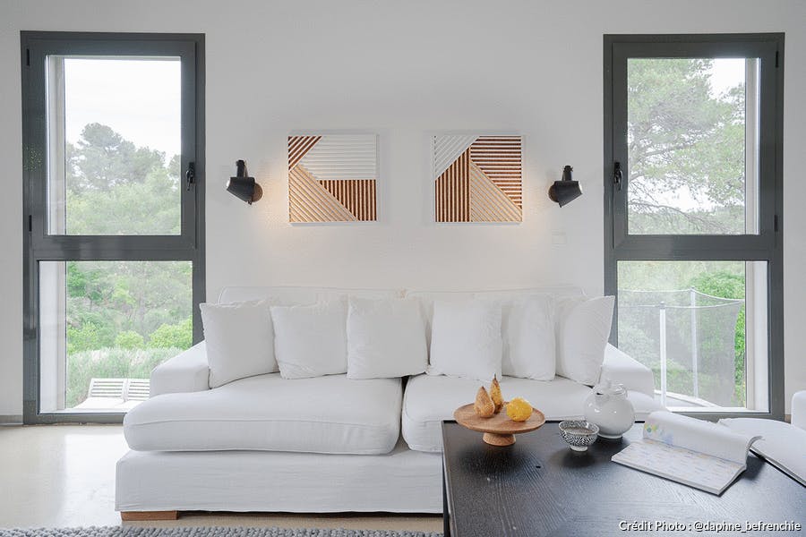 un salon avec un canapé blanc et des tableaux en bois
