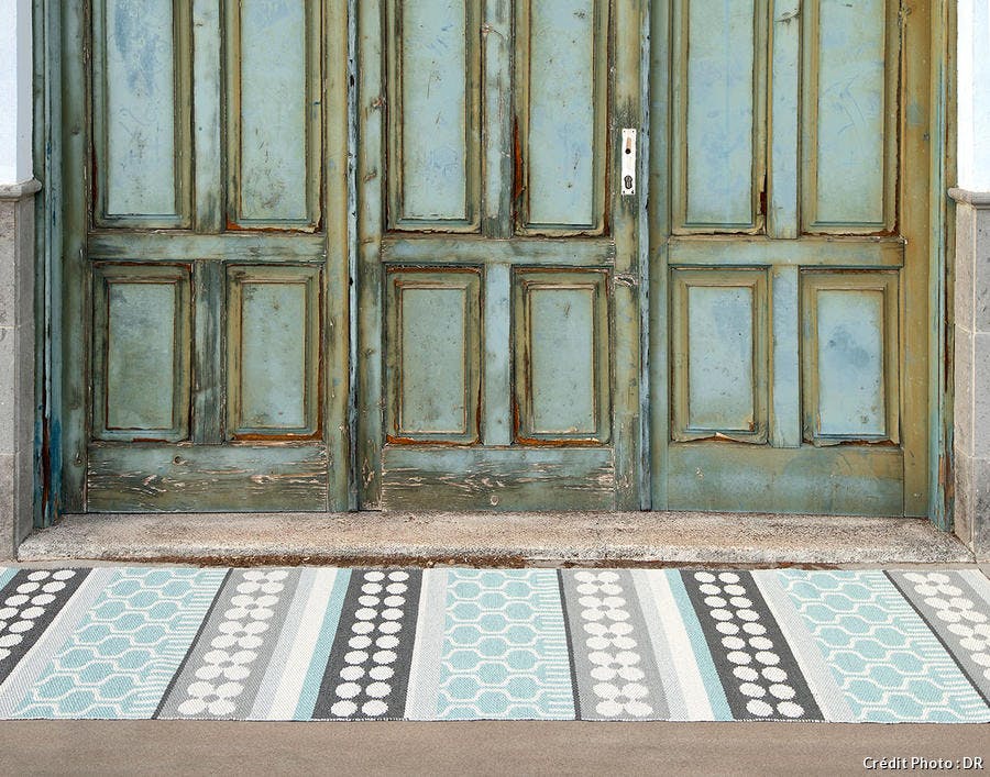 tapis extérieur graphique posé devant une porte ancienne