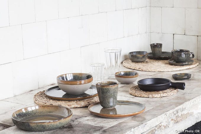 Des plats et des tasses en céramique artisanale sur un plan de travail en pierre brute