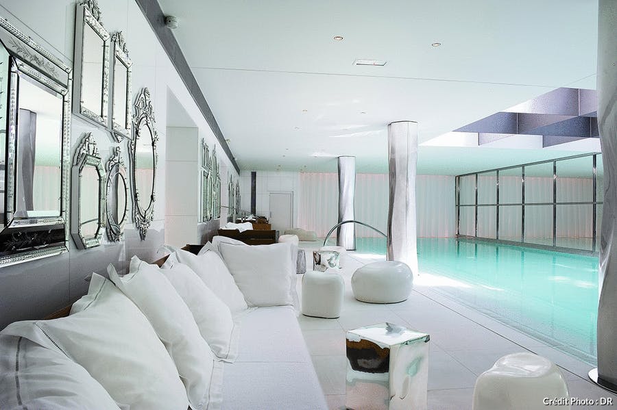 une piscine d'hôtel luxueuse tout en blanc avec une verrière en métal