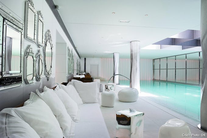 une piscine d'hôtel luxueuse tout en blanc avec une verrière en métal