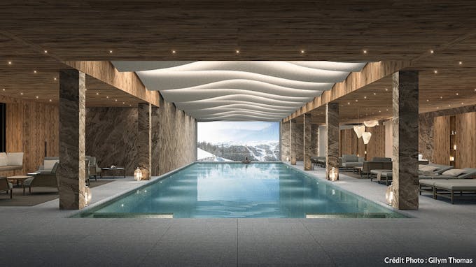 une piscine d'hôtel luxueuse sous-sol avec des murs en pierre et un plafond en bois avec vue sur la montagne
