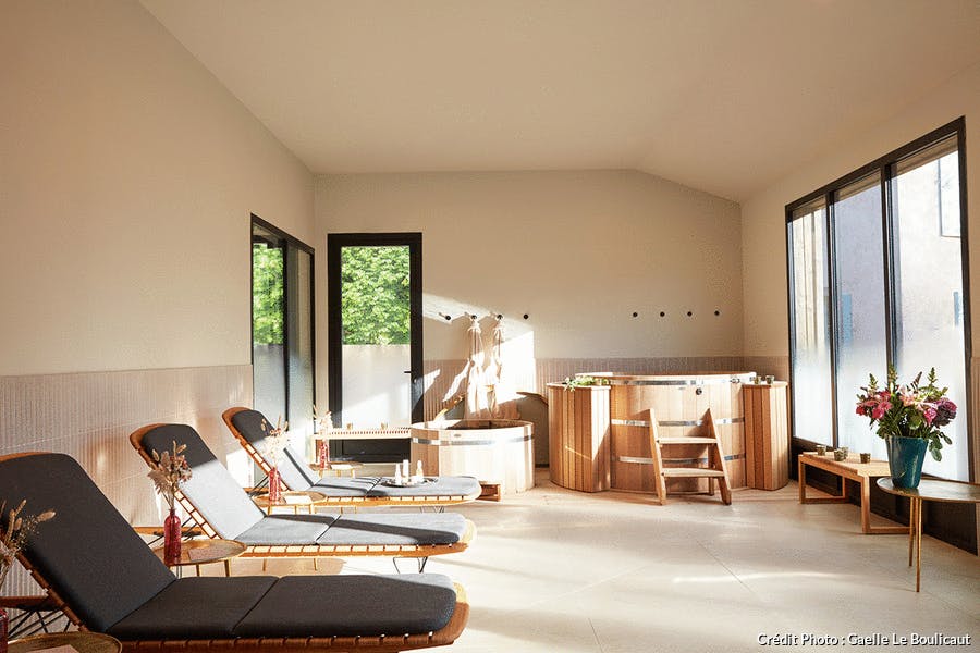 un spa hors sol en bois dans une pièce en béton avec des chaises longues de style scandinave