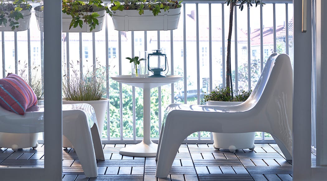 Un balcon avec salon de jardin blanc et jardinières assorties