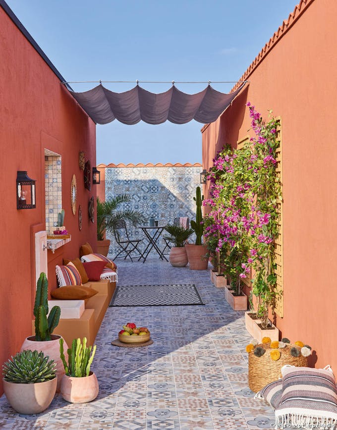 Patio avec murs de chaux et sol en carreaux décorés, jardinières en terre cuite et linge de maison coloré