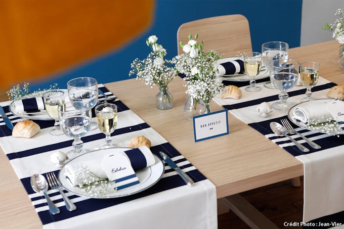 Des sets de tables rayés blanc et bleu marine posés sur une table dressée.