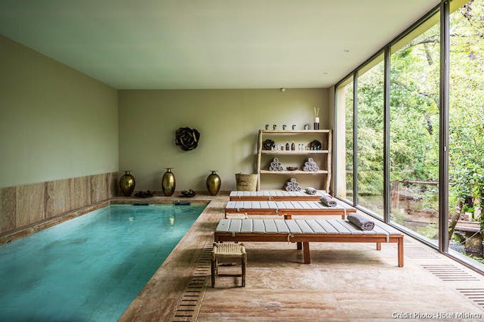 un spa d'hôtel avec un couloir de nage et des loungers en bois