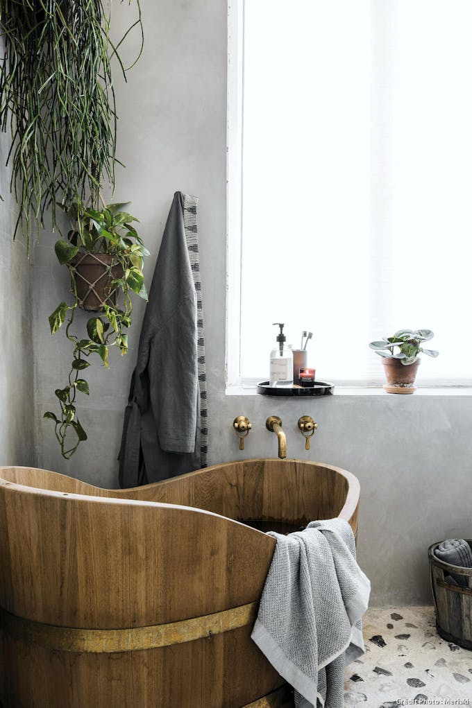 Une salle de bains en béton et une baignoire en bois