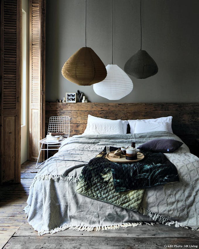 Chambre cosy avec tête de lit en bois brut, plaid en velours et luminaires en papier