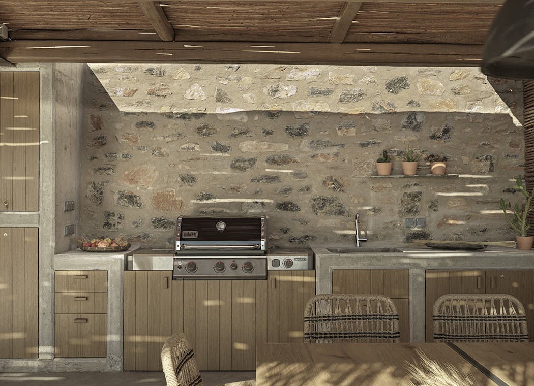 une cuisine extérieure en bois et métal contre un mur en pierres sous une tonnelle traditionnelle.