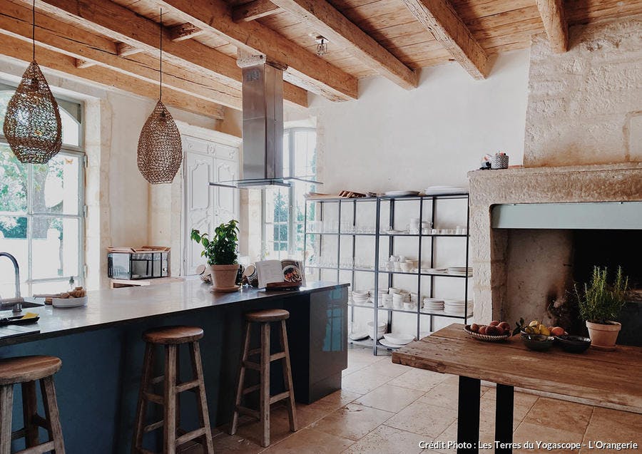 une cuisine wabi sabi ouverte sur la salle à manger avec un sol en tomettes et un plafond en bois