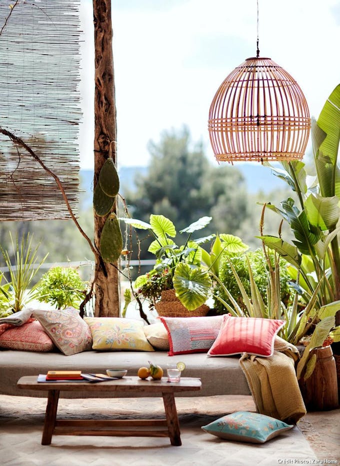 Salon ouvert sur l'extérieur, plantes exotiques et table basse en bois.