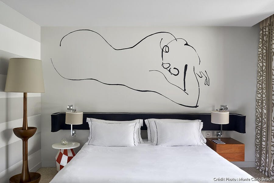 Une chambre blanche avec fresque au dessus du lit.