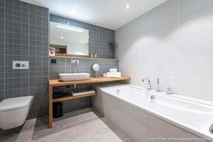 Grande salle de bains simple et pratique dans les tons de blanc et gris carrelée. 