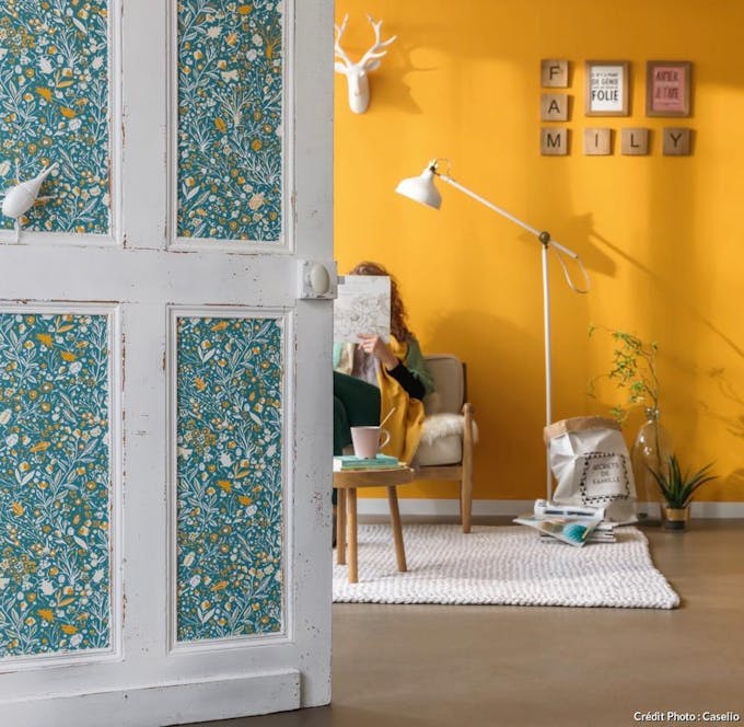 Intérieur de porte blanche vieillie avec tapisserie fleurie sur fond de mur jaune d'or.