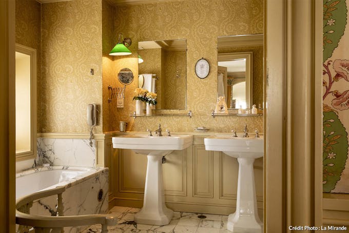 Salle de bain à éviers doubles et baignoire marbre à La Mirande. 