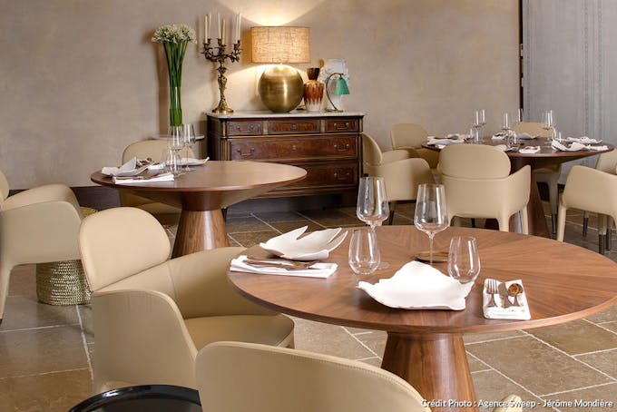 Tables rondes en bois, mobilier beige et détails décoratifs du restaurant gastronomique. 
