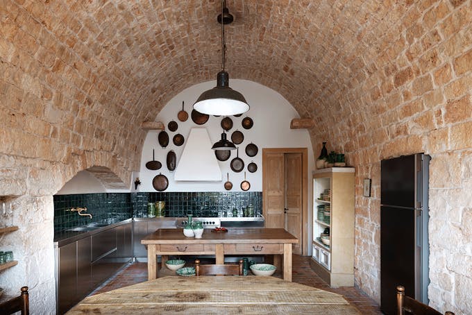 une cuisine traditionnelle avec des murs courbés en pierre et des poêles en cuivre accrochées au mur