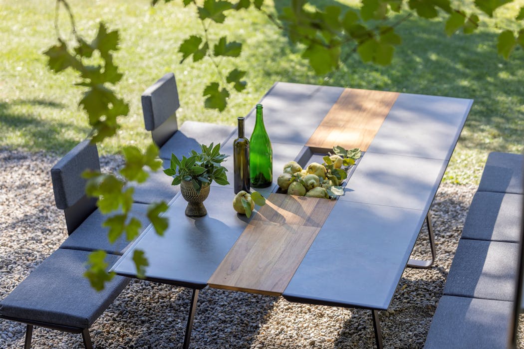 table et banc sur une terrasse près d'une pelouse