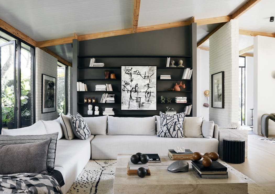 un salon de style scandinave avec un grand canapé d'angle blanc et un mur noir