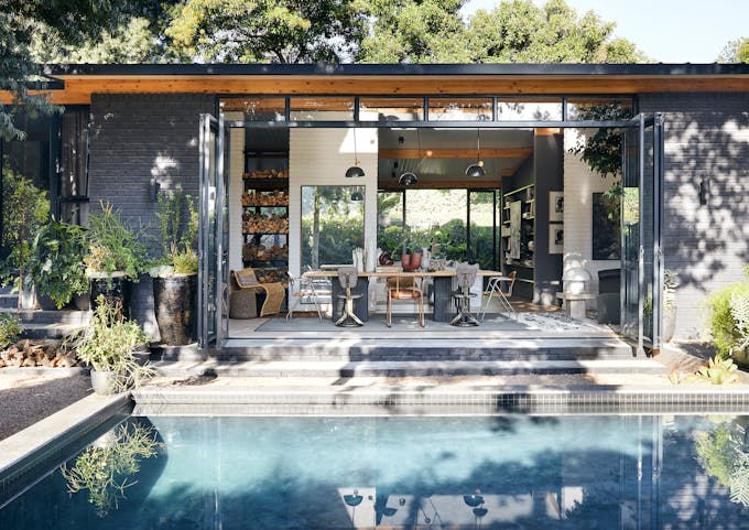 une maison de plain-pied ouverte sur un jardin avec piscine à travers de larges baies vitrées