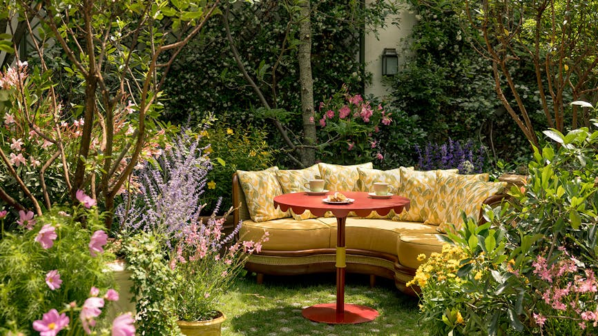 un canapé jaune dans un jardin verdoyant