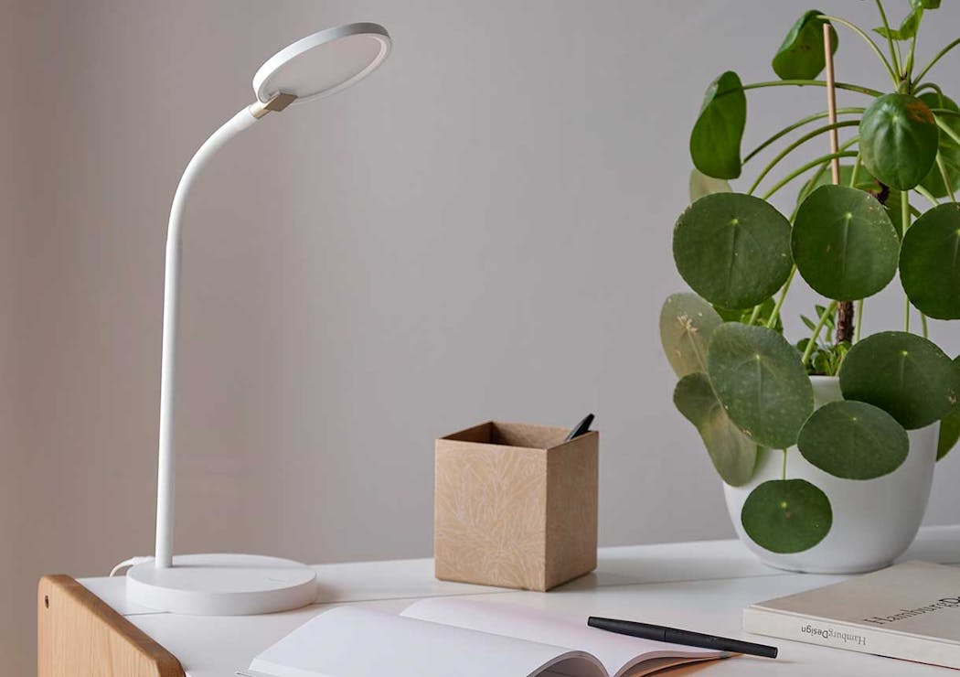 une petite lampe LED sur un bureau près d'une plante verte