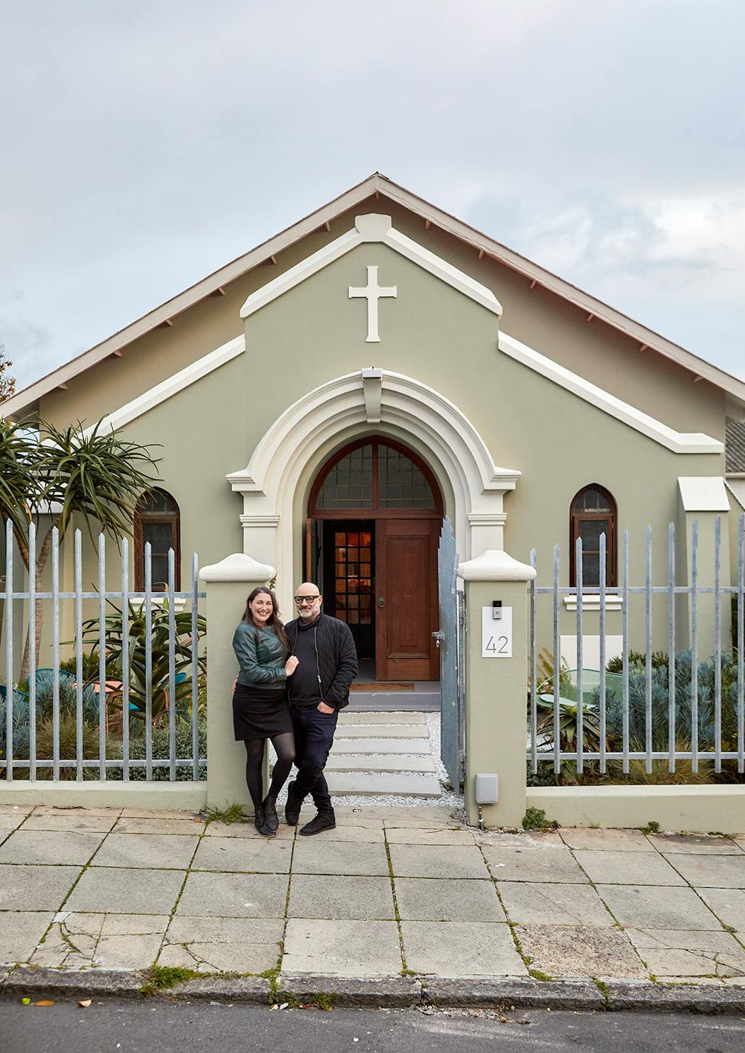 Façade extérieure et couple Haldane devant sa maison, une ancienne église repeinte aux couleurs tendres.