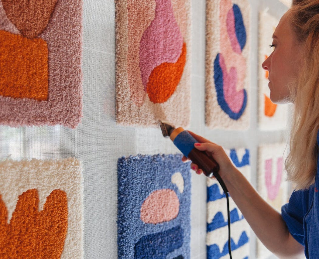 une jeune femme en train de réaliser des oeuvres murales en tuft