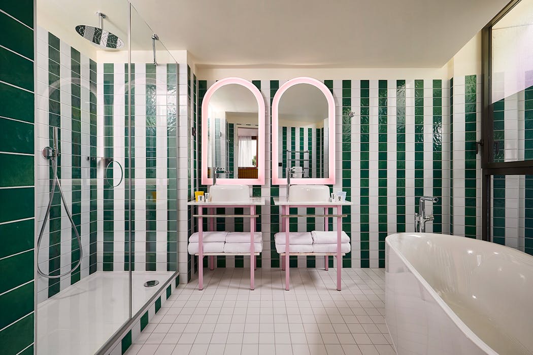 une salle de bains d'hôtel colorblock avec des miroirs rétroéclairés