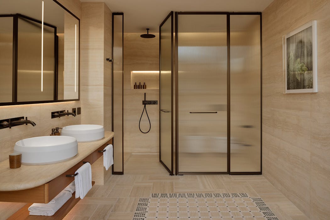 Une salle de bains d'hôtel avec une douche à l'italienne fermée par une verrière