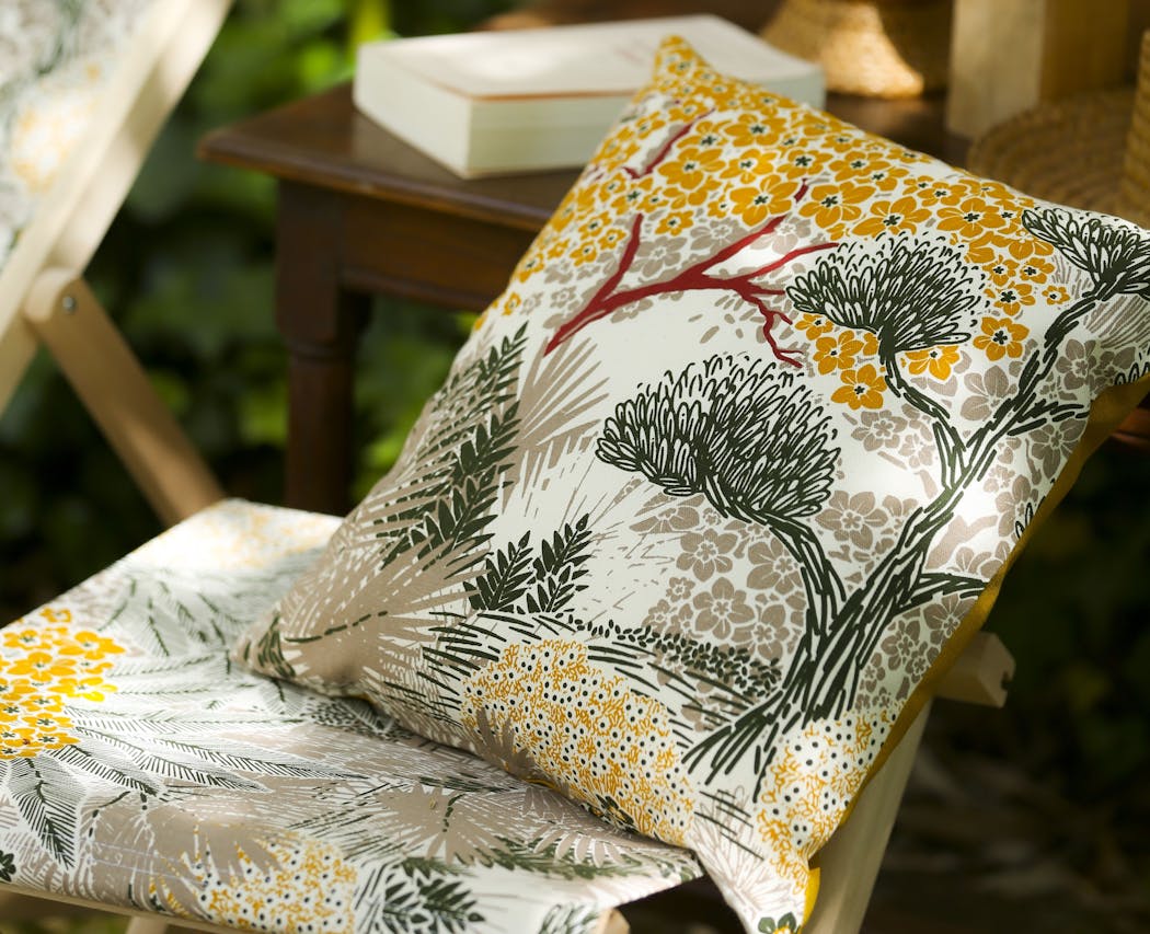 CCoussin à motifs floraux sur une chaise de jardin en bois.