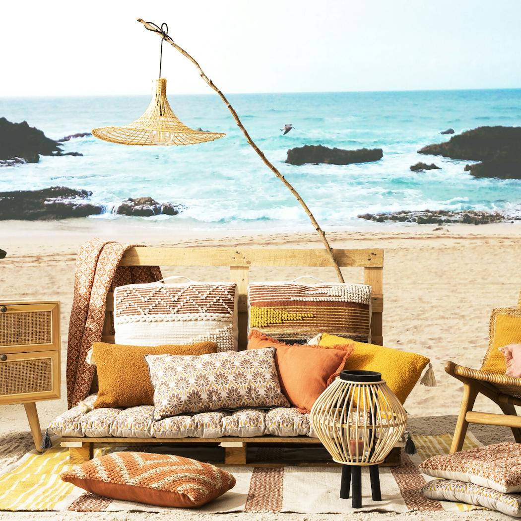 Espace détente avec coussins sur la plage face à la mer.